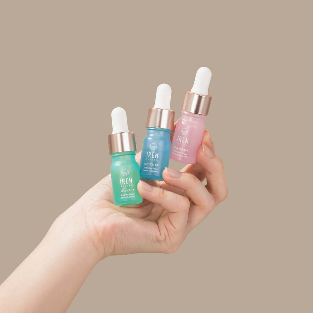 A woman's hand holding three customizable PRO MINI Skin Genie Pro + Discovery Kit serums for a spa day self-care routine from IREN Shizen.
