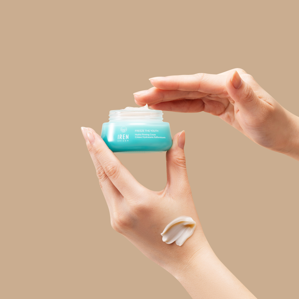 A person's hands opening a jar of FREEZE THE YOUTH Hydra Firming Cream by IREN Shizen with a dollop of the product on one finger.