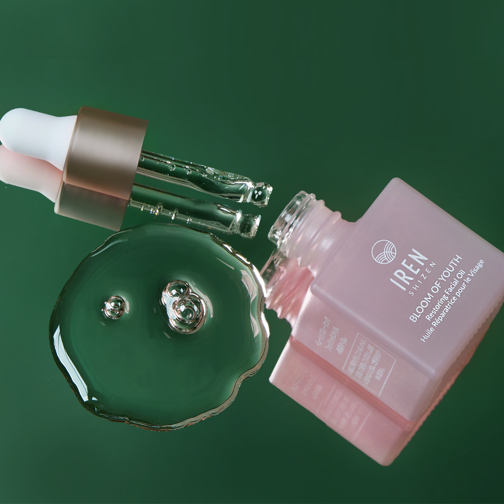 A bottle of IREN Shizen BLOOM OF YOUTH Restoring Facial Oil, customized Japanese skincare, on a green background.